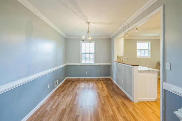 4572 Colonial Rd, Martinez, GA 30907 - unfurnished dining area with healthy amount of natural light, a chandelier, light wood-type flooring, ornamental molding, and a textured ceiling