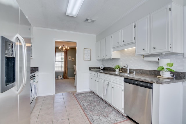 kitchen featuring visible vents, dark countertops, stainless steel appliances, white cabinetry, and a sink