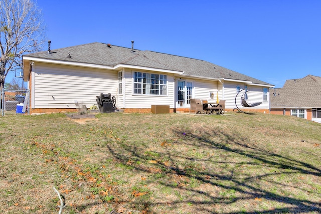 rear view of property featuring a shingled roof and a lawn