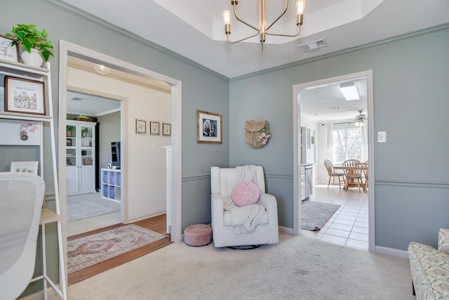 living area featuring visible vents, a raised ceiling, crown molding, and light colored carpet