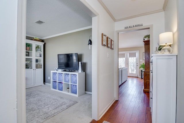 hallway with visible vents, crown molding, and baseboards