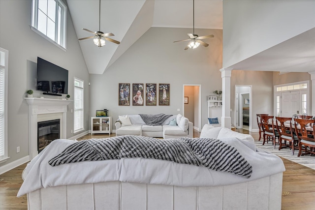 1176 Sumter Landing Cir, Evans, GA 30809 - living room featuring a ceiling fan, high vaulted ceiling, a glass covered fireplace, wood finished floors, and ornate columns
