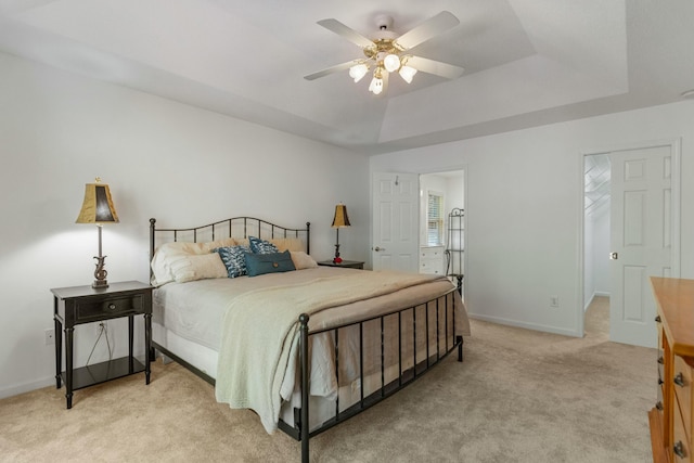 bedroom with a tray ceiling, baseboards, light colored carpet, and ceiling fan