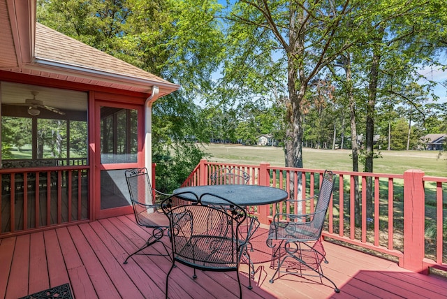 wooden terrace with outdoor dining space, a sunroom, and a lawn