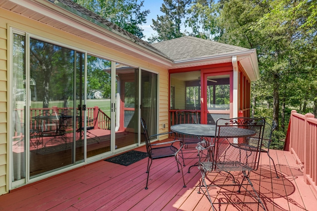 wooden deck with a sunroom and outdoor dining space