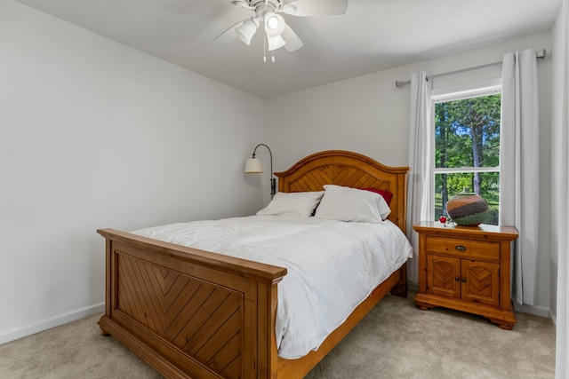 bedroom featuring light carpet, a ceiling fan, and baseboards