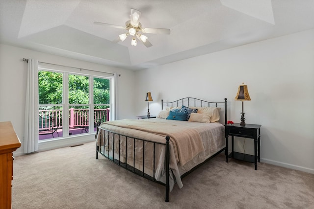 bedroom featuring a tray ceiling, carpet flooring, access to exterior, visible vents, and a ceiling fan