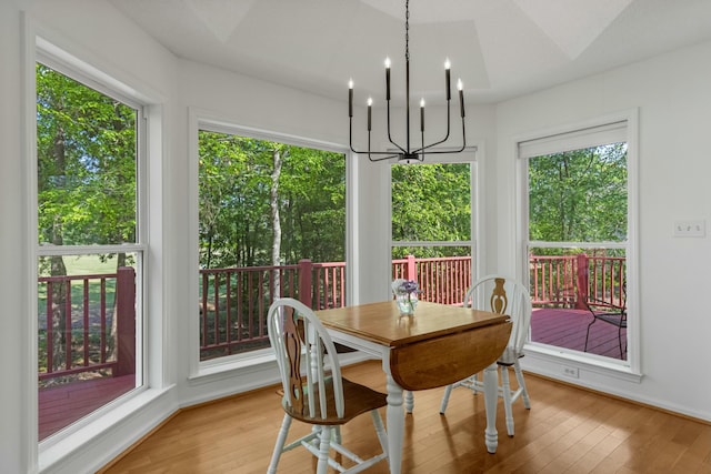 dining area featuring light wood-type flooring, baseboards, and a notable chandelier
