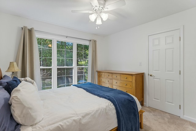 bedroom featuring light carpet, baseboards, and ceiling fan