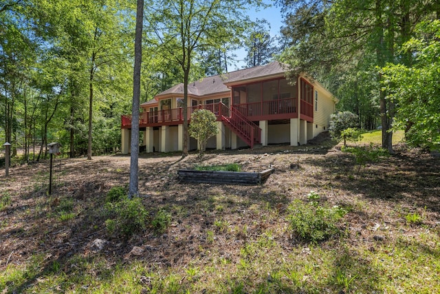 rear view of house featuring a wooden deck, a sunroom, stairway, and roof with shingles