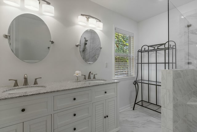 bathroom with double vanity, marble finish floor, a sink, and a walk in shower