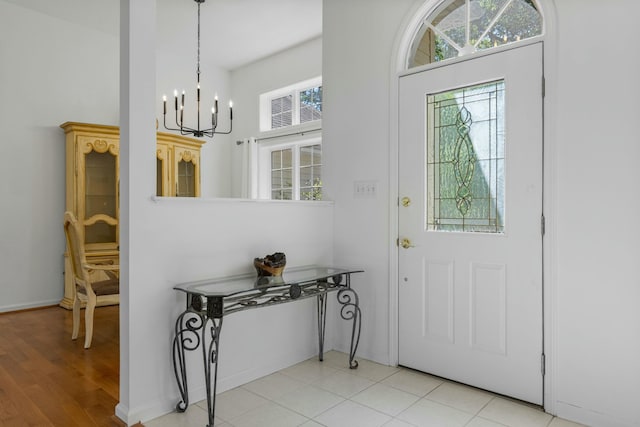 foyer with baseboards, a notable chandelier, and light wood-style floors