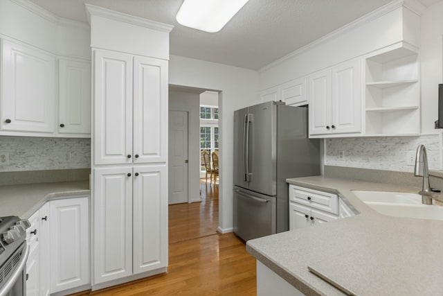 kitchen featuring white cabinets, light wood-style floors, stainless steel appliances, and a sink