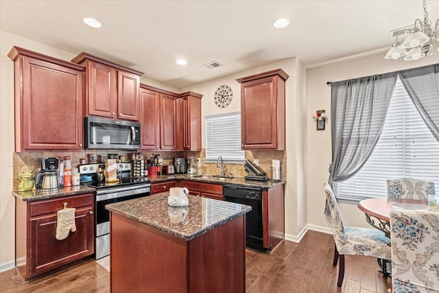 kitchen with a center island, dark wood-type flooring, sink, dark stone countertops, and appliances with stainless steel finishes