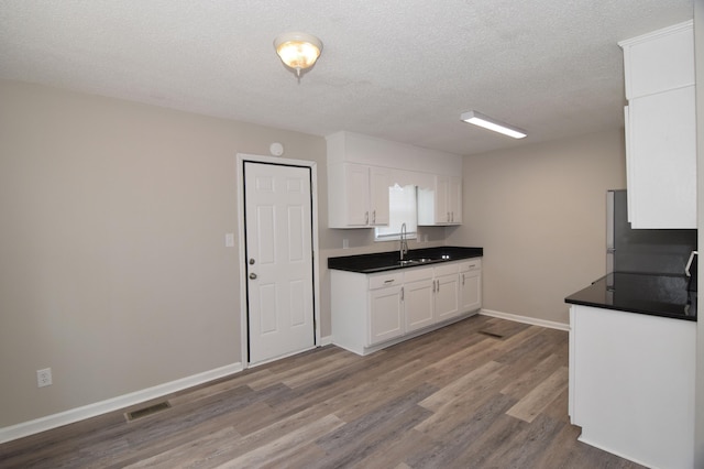 3528 Bullock Ave, Augusta, GA 30906 - kitchen featuring a sink, white cabinets, dark wood-style flooring, dark countertops, and baseboards