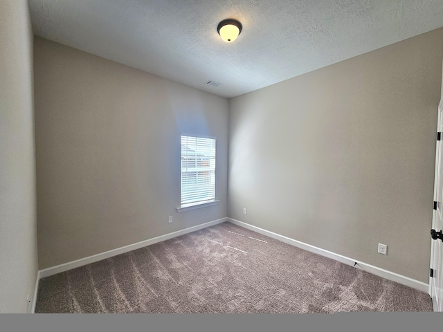 carpeted spare room featuring a textured ceiling, visible vents, and baseboards