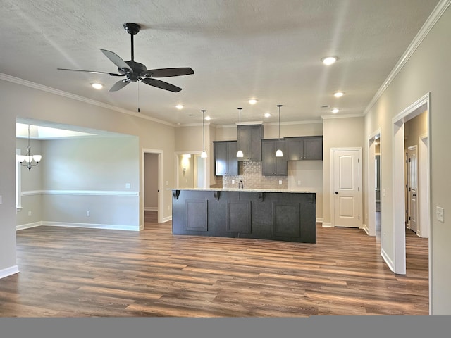 kitchen featuring an island with sink, dark wood-style flooring, light countertops, backsplash, and ceiling fan with notable chandelier