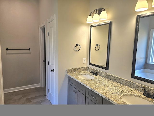 full bathroom with double vanity, a bathtub, baseboards, and a sink