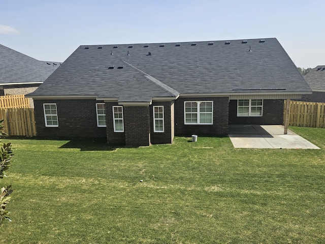 back of property with brick siding, a lawn, a patio area, and fence