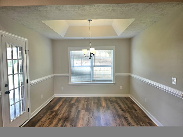 unfurnished dining area featuring a healthy amount of sunlight, baseboards, a raised ceiling, and dark wood-style flooring