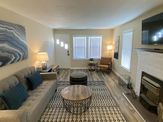 living room featuring a brick fireplace, a wealth of natural light, and wood-type flooring