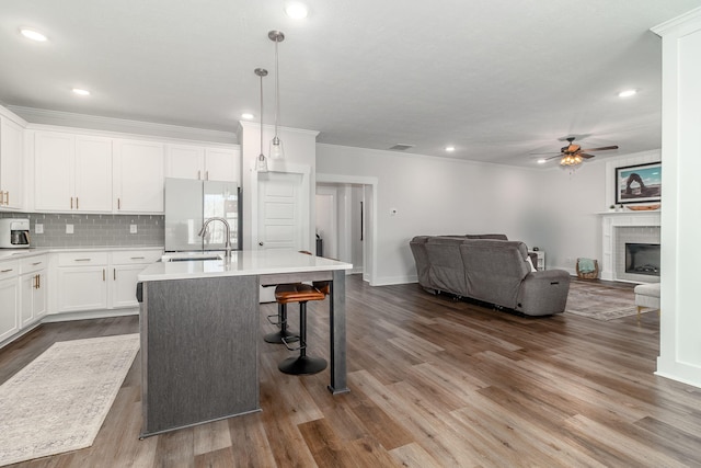 kitchen featuring a sink, open floor plan, backsplash, freestanding refrigerator, and an island with sink