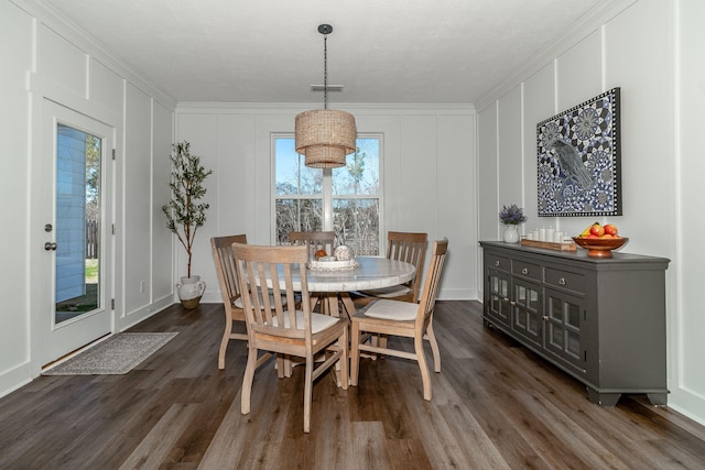 dining space with dark wood-style floors, visible vents, a decorative wall, and ornamental molding