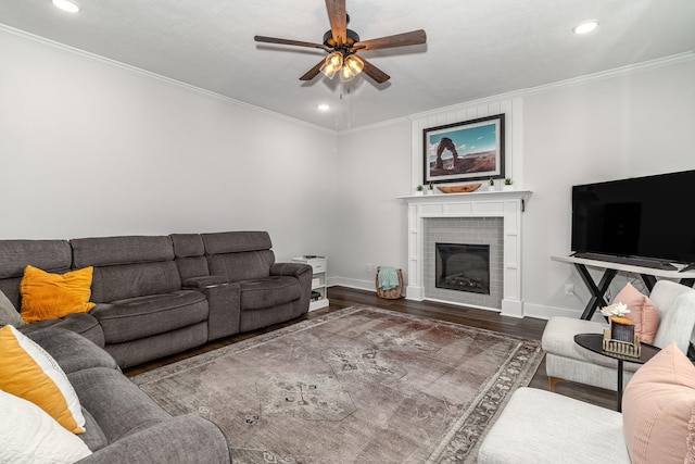 living room with crown molding, a brick fireplace, ceiling fan, wood finished floors, and baseboards