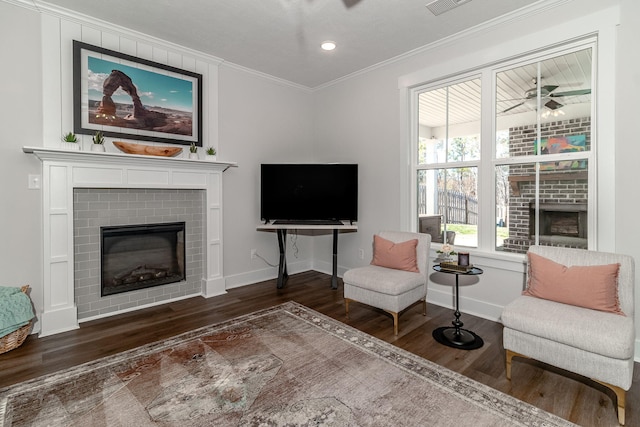 sitting room featuring recessed lighting, wood finished floors, baseboards, ornamental molding, and a brick fireplace