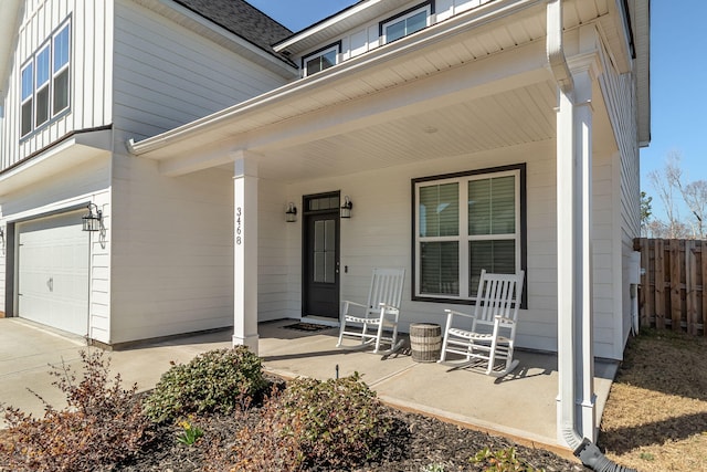 entrance to property featuring a porch, board and batten siding, an attached garage, and fence