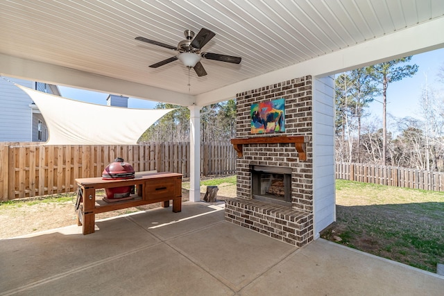 view of patio / terrace with an outdoor brick fireplace, a ceiling fan, and a fenced backyard