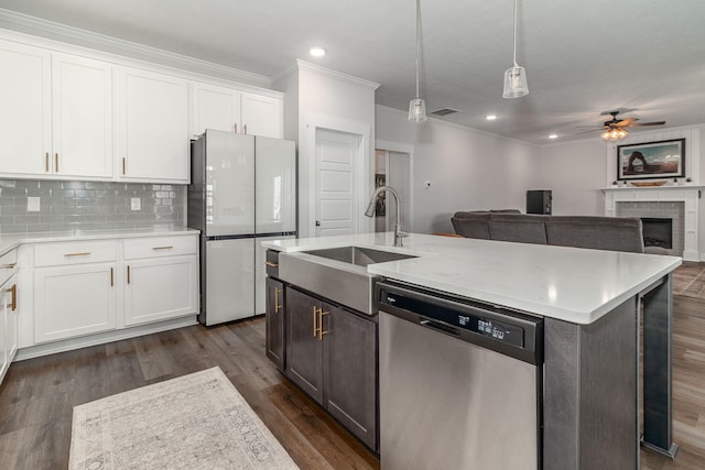 kitchen with a sink, white cabinetry, light countertops, stainless steel dishwasher, and freestanding refrigerator