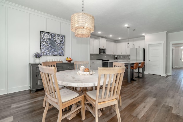 dining area with crown molding, dark wood-style flooring, recessed lighting, and a decorative wall