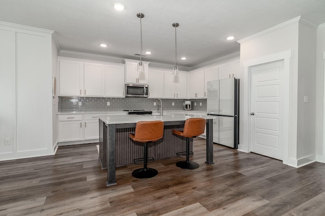 kitchen featuring stainless steel appliances, white cabinets, light countertops, ornamental molding, and a center island with sink