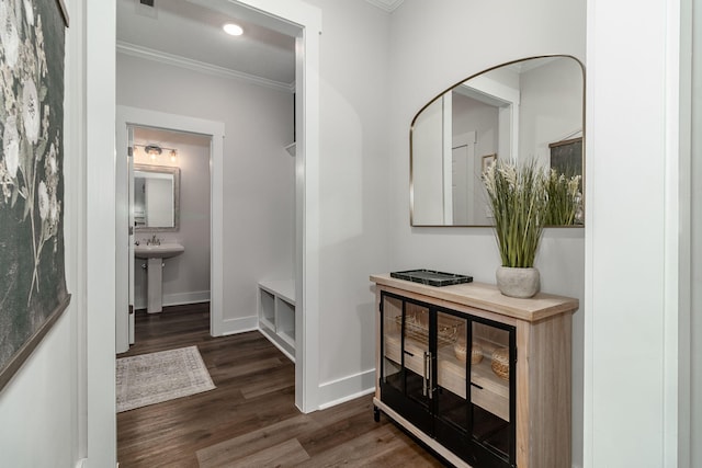 corridor featuring recessed lighting, a sink, wood finished floors, baseboards, and ornamental molding