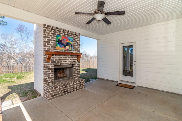 view of patio featuring an outdoor brick fireplace, fence, and a ceiling fan