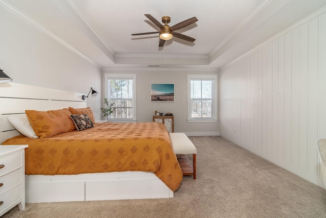 bedroom with light carpet, ceiling fan, a tray ceiling, and ornamental molding