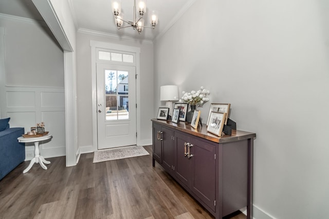 entryway with a decorative wall, a wainscoted wall, crown molding, dark wood-style floors, and an inviting chandelier