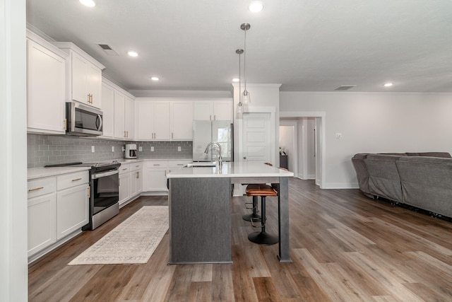 kitchen featuring tasteful backsplash, a center island with sink, appliances with stainless steel finishes, open floor plan, and a sink