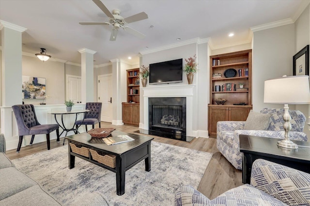 living room with light wood-type flooring, ceiling fan, and ornamental molding