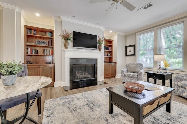 living room with ceiling fan, ornamental molding, a wealth of natural light, and light hardwood / wood-style flooring