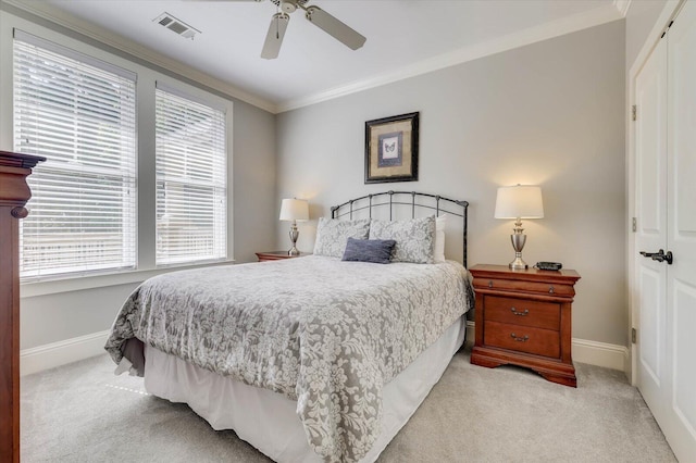 bedroom featuring ceiling fan, light colored carpet, ornamental molding, and a closet