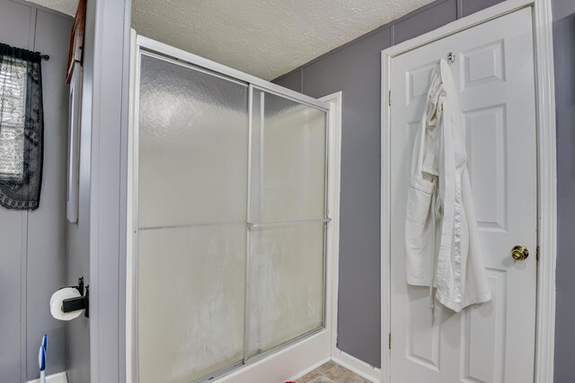 bathroom with an enclosed shower and a textured ceiling