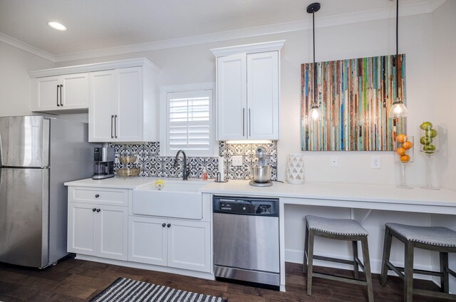 kitchen with ornamental molding, stainless steel appliances, sink, decorative light fixtures, and white cabinetry