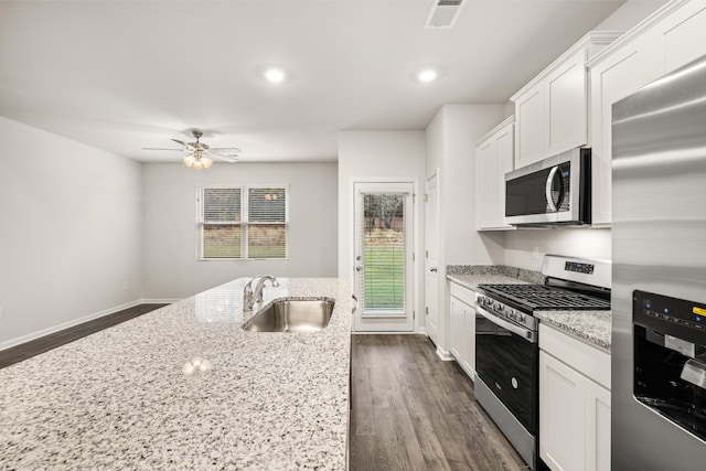 kitchen with appliances with stainless steel finishes, white cabinets, light stone countertops, and sink