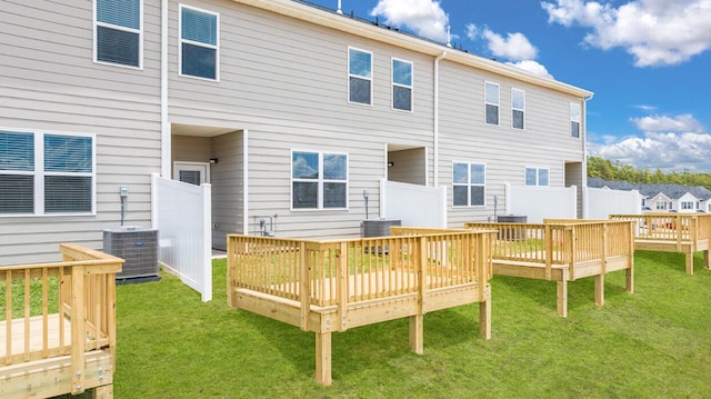 rear view of property featuring central AC unit, a deck, and a lawn