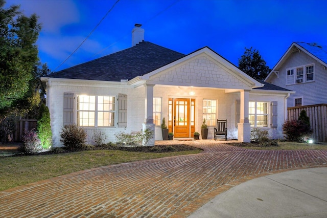 view of front of home with covered porch, a shingled roof, a chimney, and brick siding