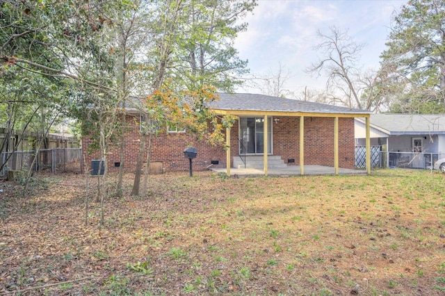 back of house featuring a yard, crawl space, brick siding, and a fenced backyard