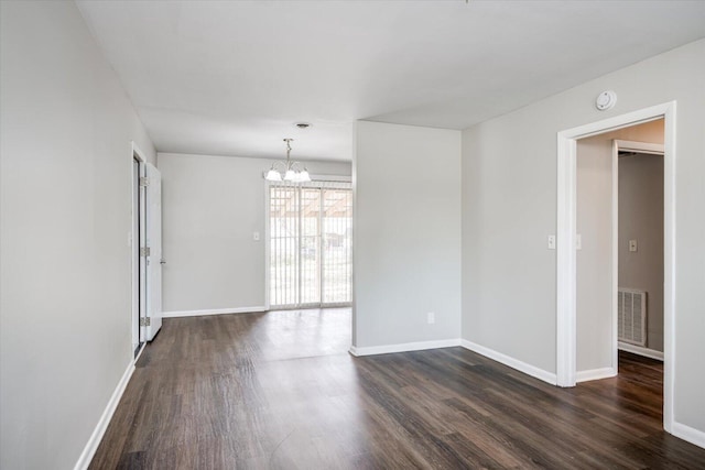 spare room with visible vents, baseboards, dark wood-type flooring, and a chandelier