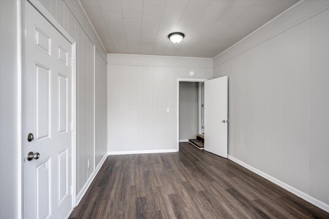 spare room featuring baseboards and dark wood-type flooring